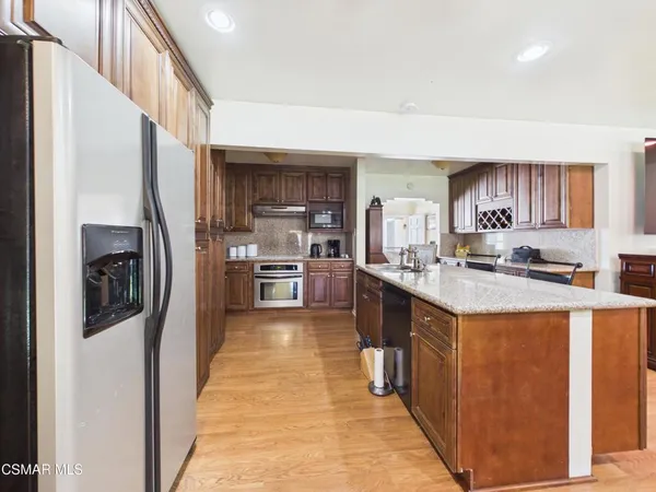a kitchen with stainless steel appliances granite countertop a refrigerator a stove and a sink with wooden floor