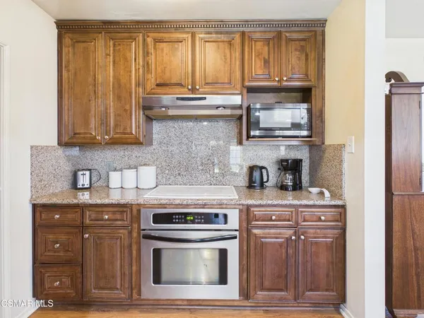 a kitchen with granite countertop a stove top oven cabinetry and refrigerator