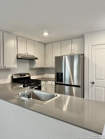 a kitchen with stainless steel appliances granite countertop a refrigerator a sink a stove a microwave and a refrigerator