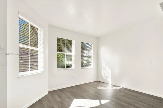 a view of an empty room with wooden floor and windows