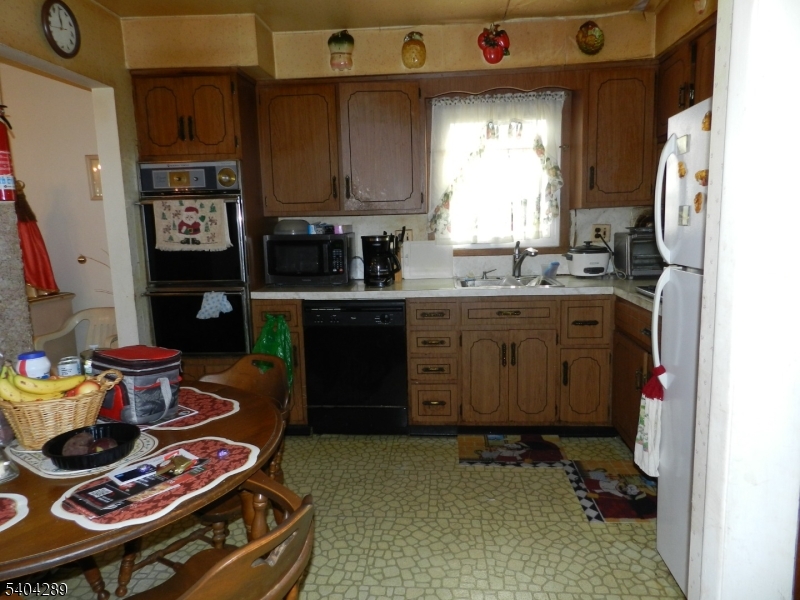 2442 Terrill Road Union, NJ 07083 - Photo 8 of 15 a kitchen with stainless steel appliances granite countertop a stove a refrigerator and a dining table with wooden floor