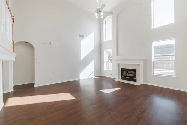 an empty room with wooden floor fireplace and windows
