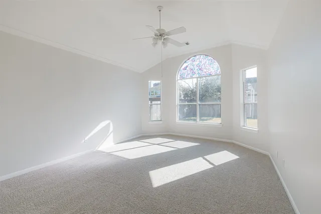 an empty room with windows and fan