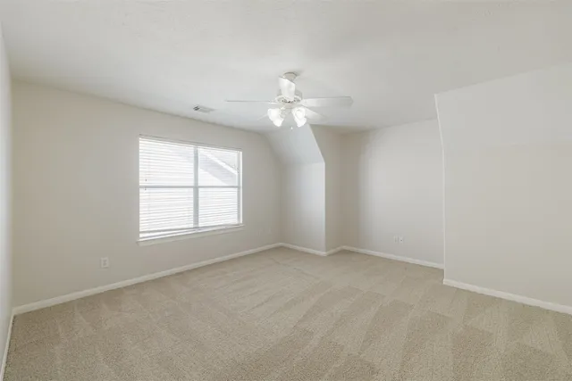 an empty room with chandelier fan and windows