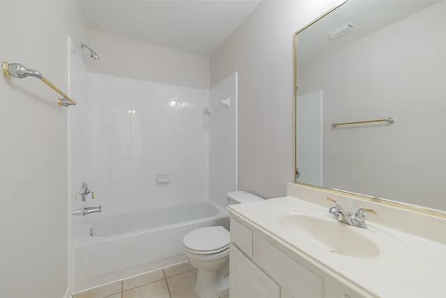 a bathroom with a bathtub shower sink vanity mirror and toilet