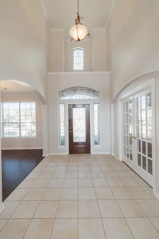 a view of an empty room with window and chandelier