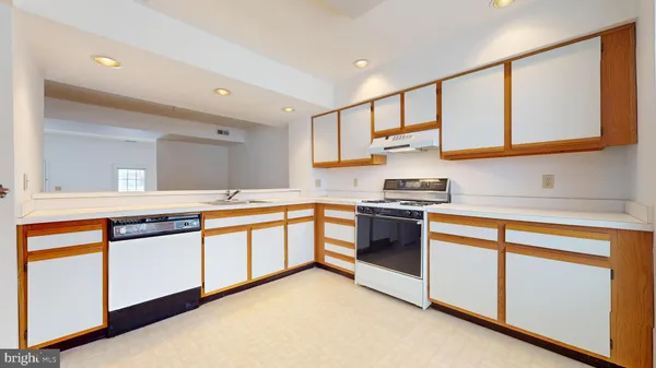 a kitchen with stainless steel appliances a refrigerator a sink and white cabinets