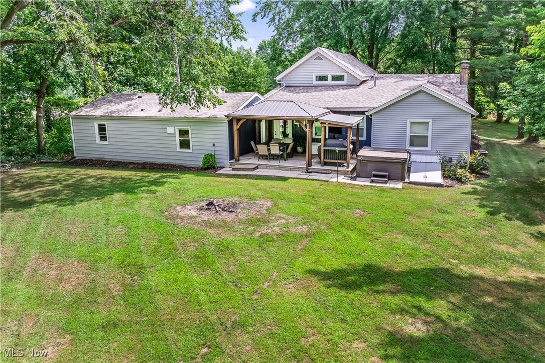 6170 Oberlin Road Amherst, OH 44001 - Photo 2 of 39 Back of house with a hot tub, a yard, a chimney, a patio, and a shingled roof