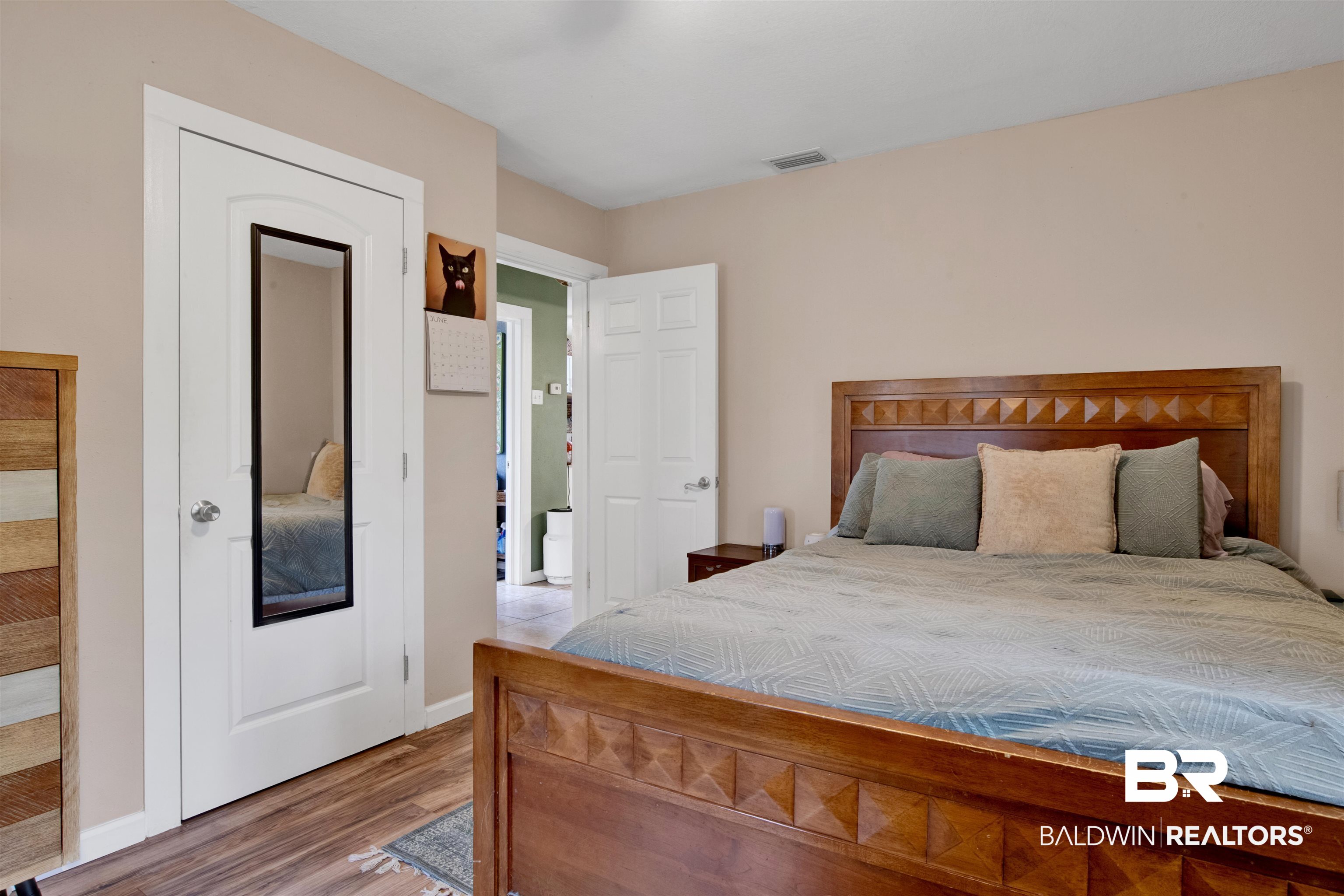 1100 North Pine Street Foley, AL 36535 - Photo 12 of 30 Bedroom featuring wood-finish flooring, a white door with an integrated mirror, and a neutral wall color