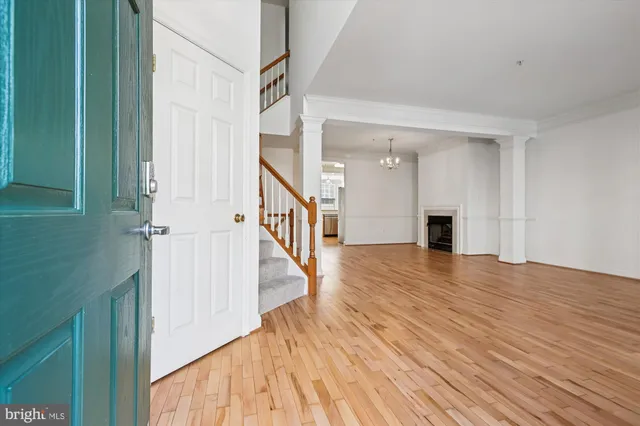 a view of an empty room with wooden floor and stairs