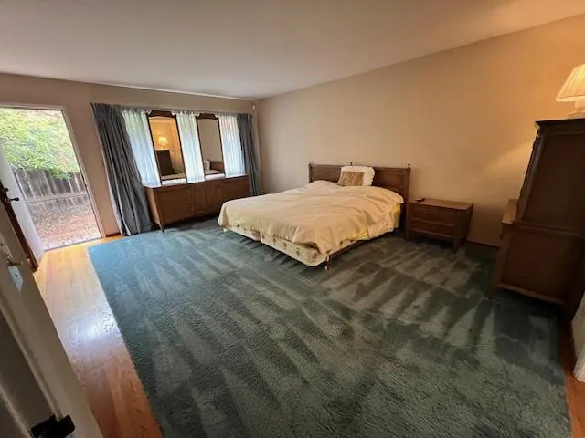 a spacious bedroom with a bed and wooden floor