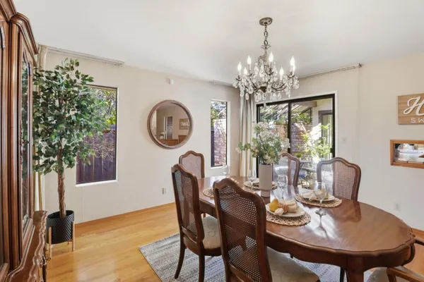 a kitchen with stainless steel appliances granite countertop a stove a sink a refrigerator a dining table and chairs with wooden floor