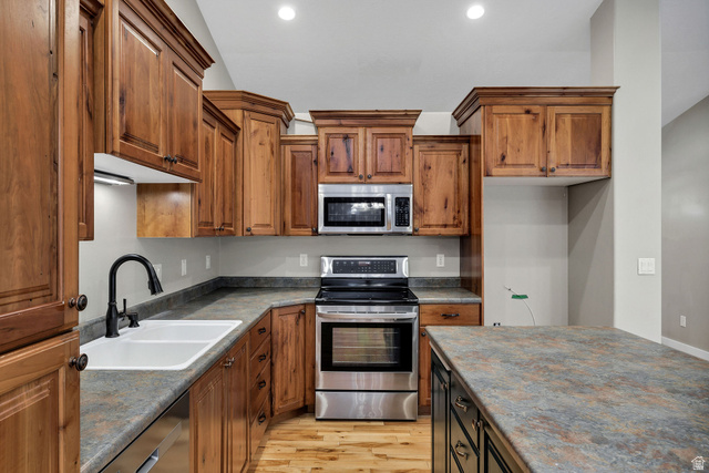 2912 South 1080th Street West Logan, UT 84321 - Photo 31 of 43 Kitchen featuring wood cabinetry with crown molding, stainless steel appliances, a double basin sink with a matte black faucet, and stone-finish countertops