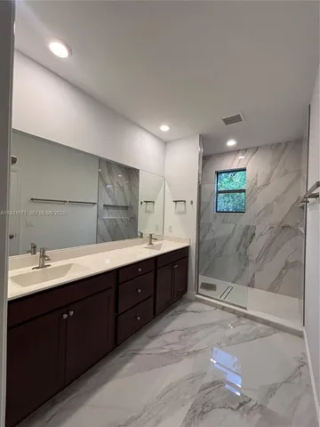 a bathroom with a double vanity sink mirror and shower