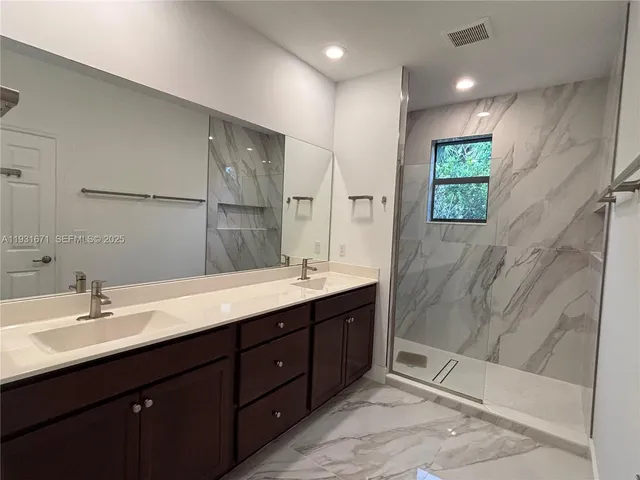 a bathroom with a double vanity sink mirror and shower