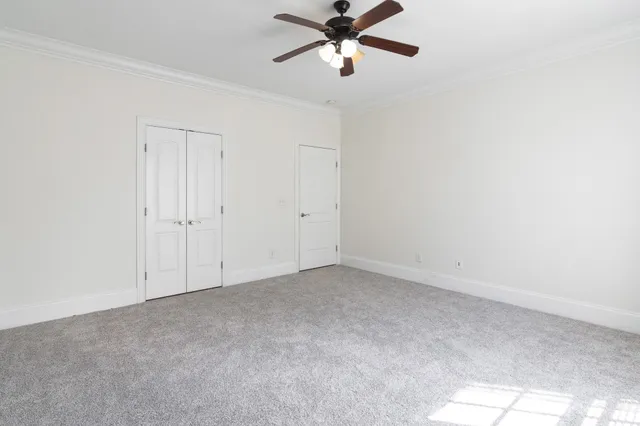 a view of an empty room and chandelier fan