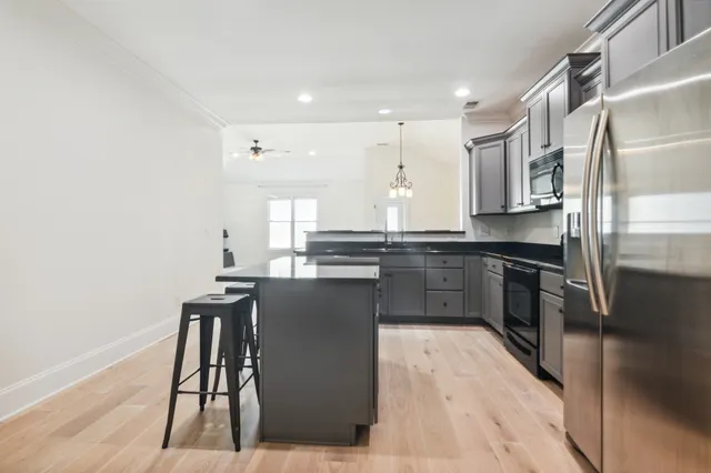 a kitchen with stainless steel appliances a sink a stove a microwave a refrigerator and cabinets