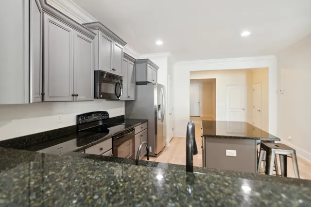 a kitchen with kitchen island a counter top space a sink stainless steel appliances and cabinets
