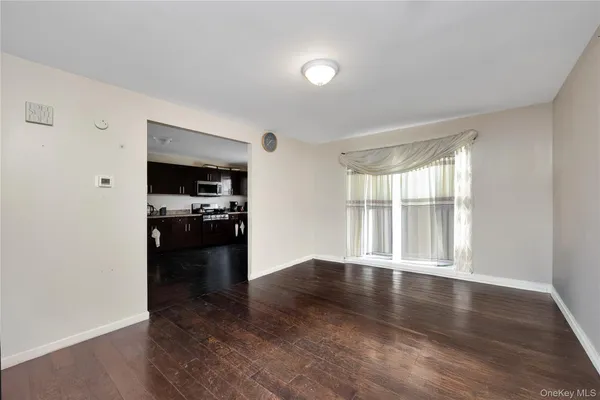 a view of a kitchen and an empty room with wooden floor