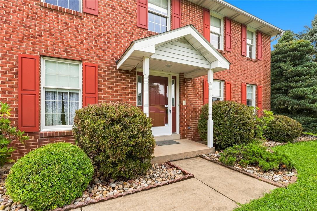 6090 Stone Post Road Bath, PA 18014 - Photo 5 of 57 A classic brick facade is enhanced by vibrant red shutters and meticulously maintained landscaping, offering a welcoming entry.