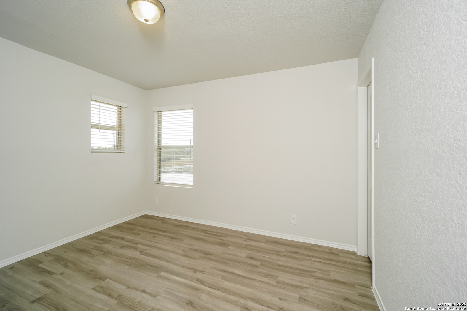 5130 Blue Ranch San Antonio, TX 78222 - Photo 12 of 17 an empty room with wooden floor and windows