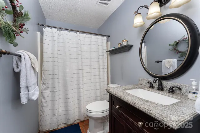 a bathroom with a granite countertop toilet sink and mirror