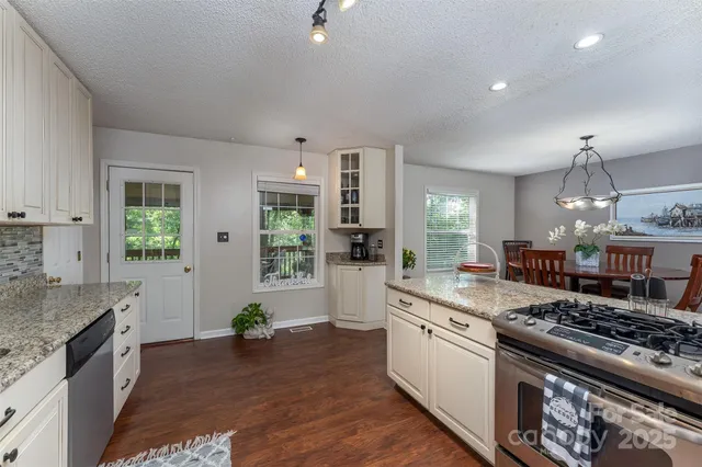 a large white kitchen with stainless steel appliances granite countertop a stove and a sink
