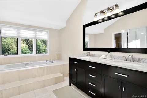 a bathroom with a tub a double vanity sink and mirror