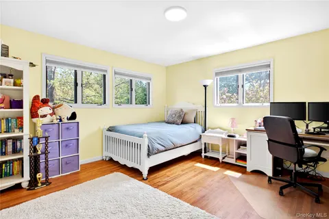 a bedroom with a bed and a computer on the desk next to a window