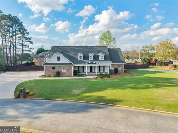 a view of a big house with a big yard and large trees