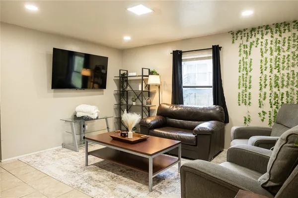 a living room with furniture a flat screen tv and a large window