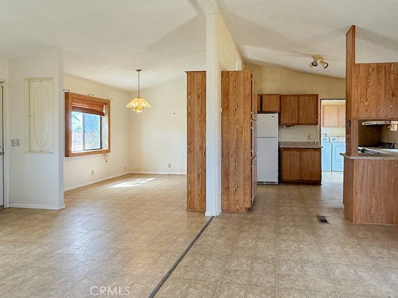 6450 Maricopa Road Phelan, CA 92371 - Photo 4 of 16 an empty room with a kitchen view and a refrigerator
