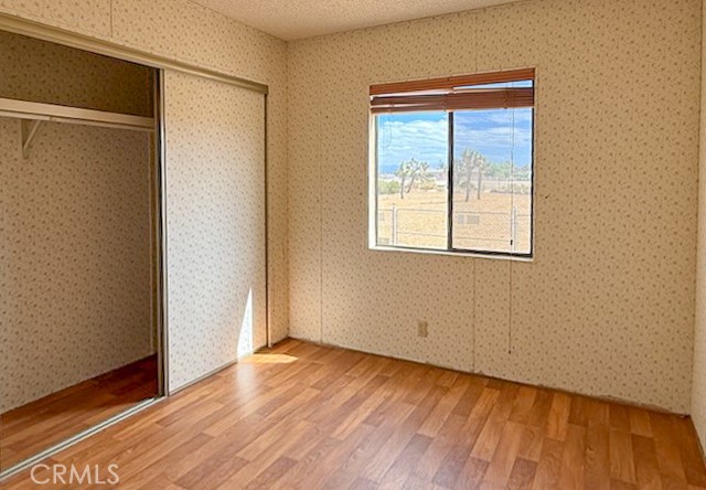 6450 Maricopa Road Phelan, CA 92371 - Photo 9 of 16 an empty room with wooden floor and windows