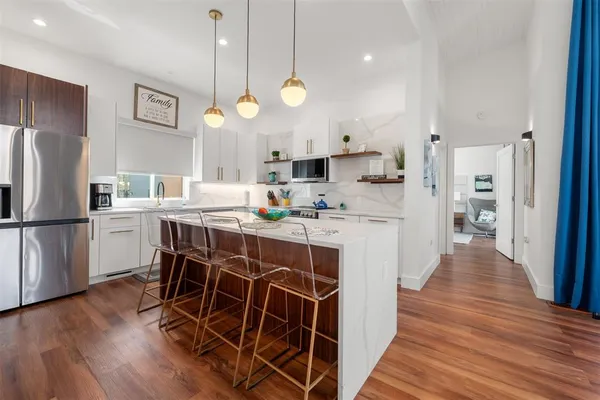 a kitchen with stainless steel appliances a table chairs wooden floors and a view of living room