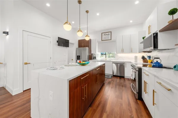 a large kitchen with a lot of counter space and wooden floor