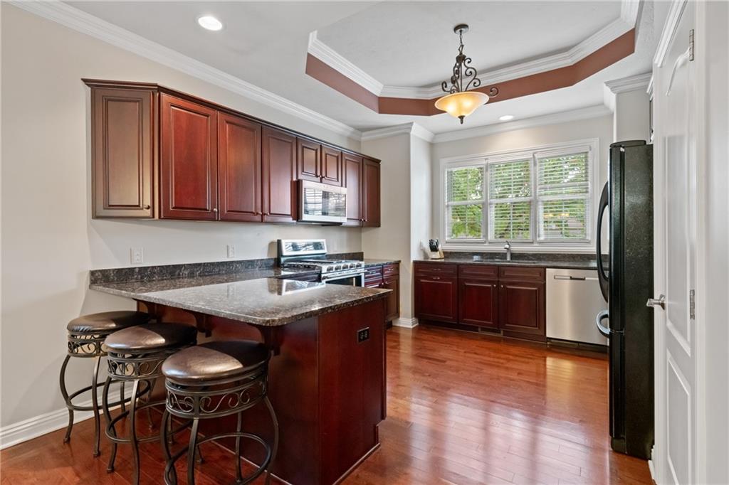 1737 Waterleaf Drive Sewickley, PA 15143 - Photo 6 of 34 a kitchen with stainless steel appliances granite countertop a stove a refrigerator a sink a dining table and chairs with wooden floor