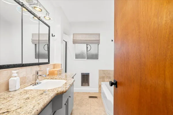 a bathroom with a granite countertop sink and a mirror