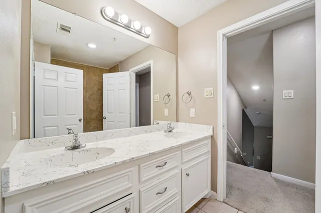 a bathroom with a granite countertop double vanity sink and mirror