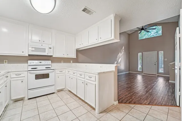 a kitchen with granite countertop white cabinets and white appliances