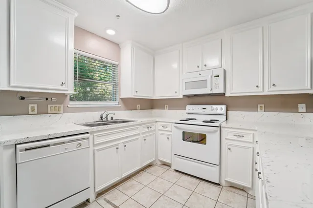 a kitchen with white cabinets appliances and a window