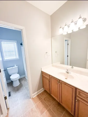 a spacious bathroom with a granite countertop sink a toilet and a mirror