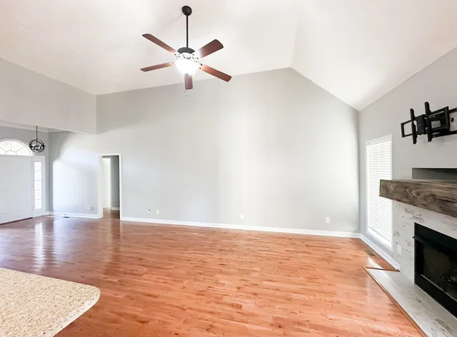a view of an empty room with a fireplace and wooden floor