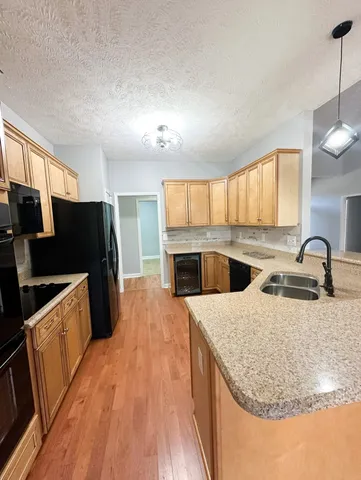 a kitchen with granite countertop a refrigerator a stove a sink dishwasher and wooden cabinets with wooden floor