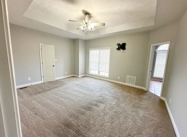 en empty room with windows and chandelier fan