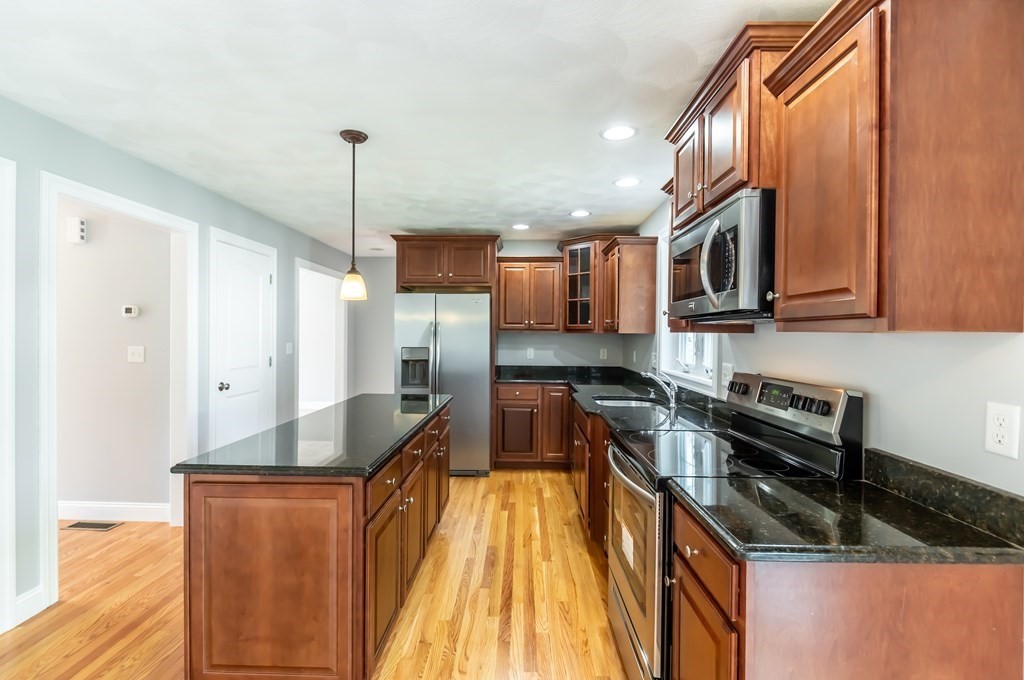12 Bell Road Tewksbury, MA 01876 - Photo 5 of 26 a kitchen with stainless steel appliances granite countertop a sink a stove and a refrigerator