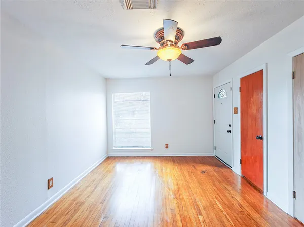 a view of an empty room with wooden floor and a window