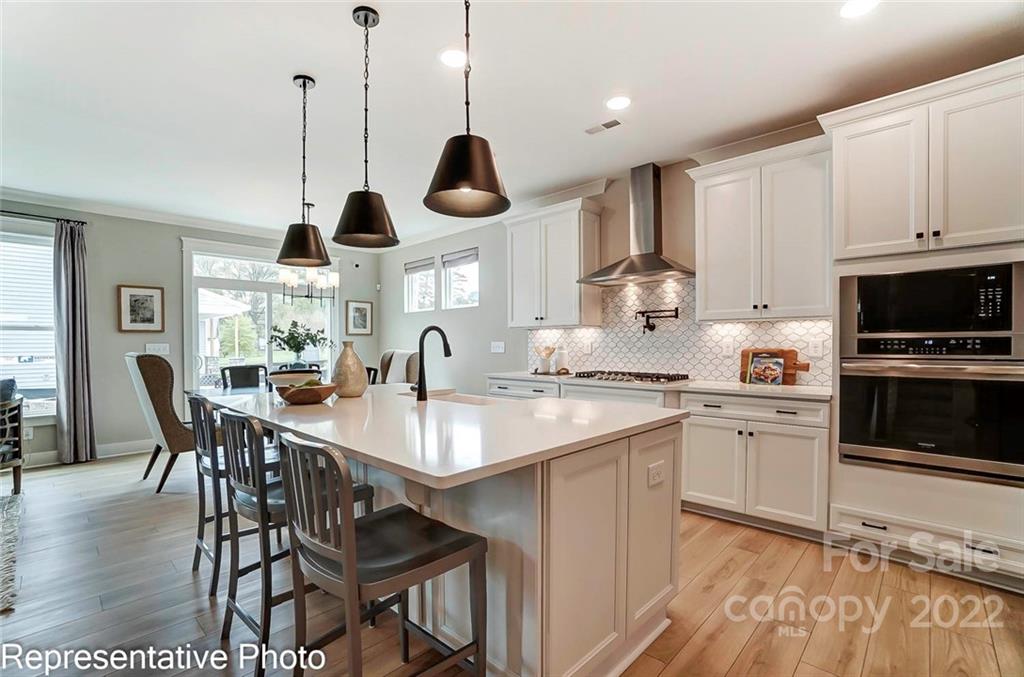 2345 Windley Drive Gastonia, NC 28054 - Photo 12 of 32 a kitchen with stainless steel appliances kitchen island granite countertop a stove a sink a dining table and chairs with wooden floor