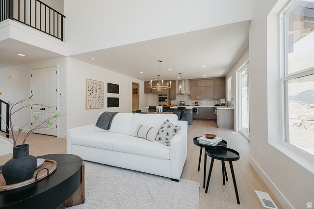 5902 Canyon Rim Road, Unit 620 Lehi, UT 84048 - Photo 18 of 78 Open-concept living space featuring wood-finish flooring, a two-story ceiling, a contemporary kitchen with stainless steel appliances, and abundant natural light from large windows