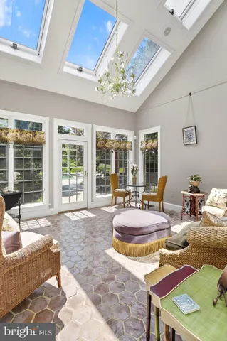 a view of a livingroom with furniture a chandelier wooden floor and windows