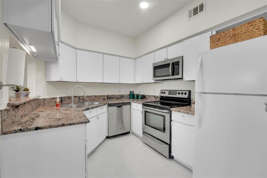 1700 Amelia Court, Unit 312 Plano, TX 75075 - Photo 9 of 30 a kitchen with stainless steel appliances granite countertop a stove top oven a sink a microwave and a refrigerator